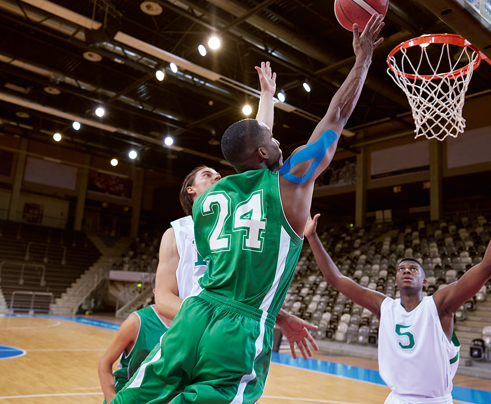 Basketball player using blue kinesiology tape on shoulder during a game. Basketball player using blue kinesiology tape on shoulder during a game.